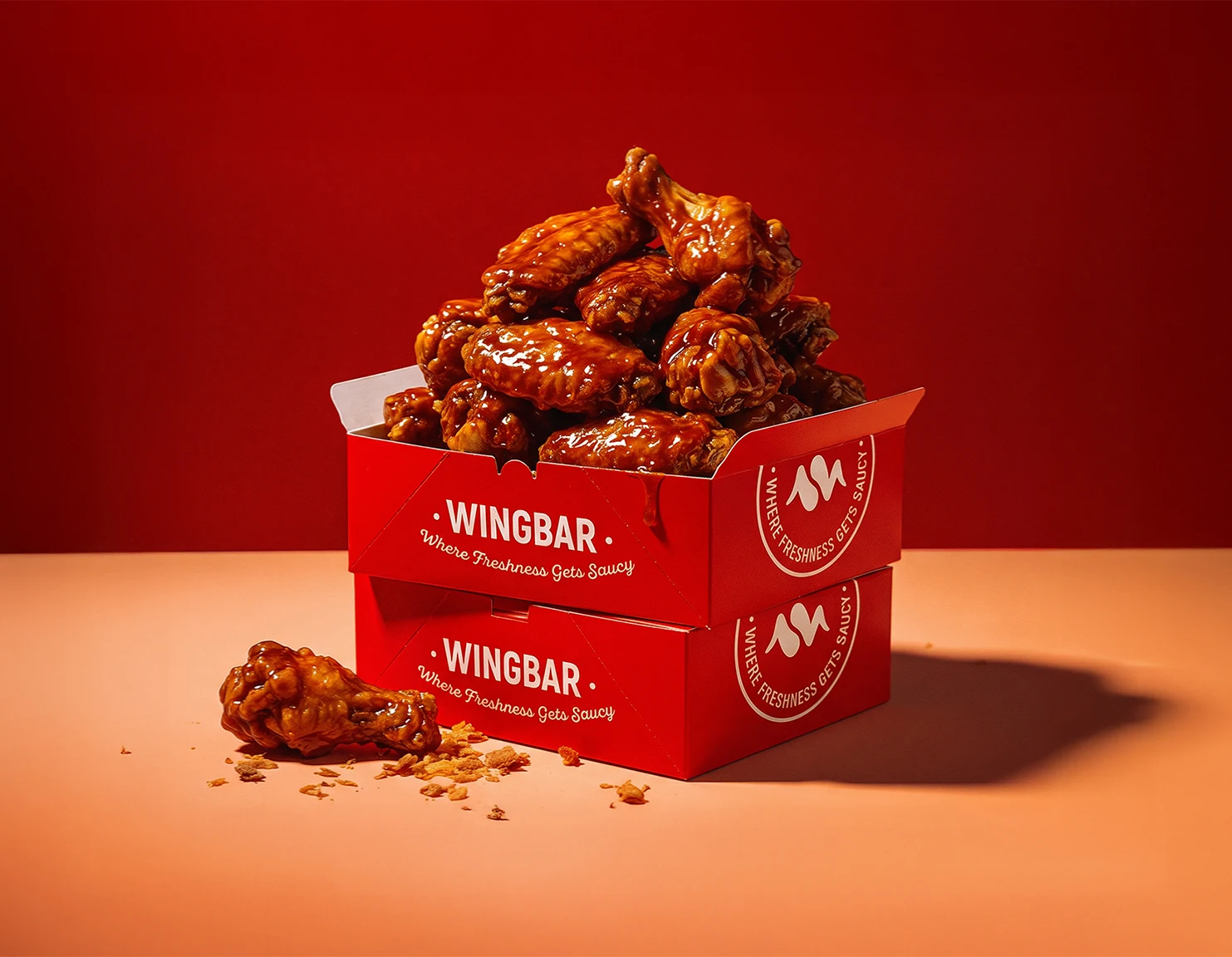 Sauced wings in red WINGBAR takeaway boxes.
