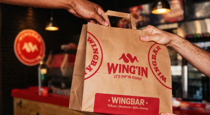 Branded paper takeaway bag handed to a customer.