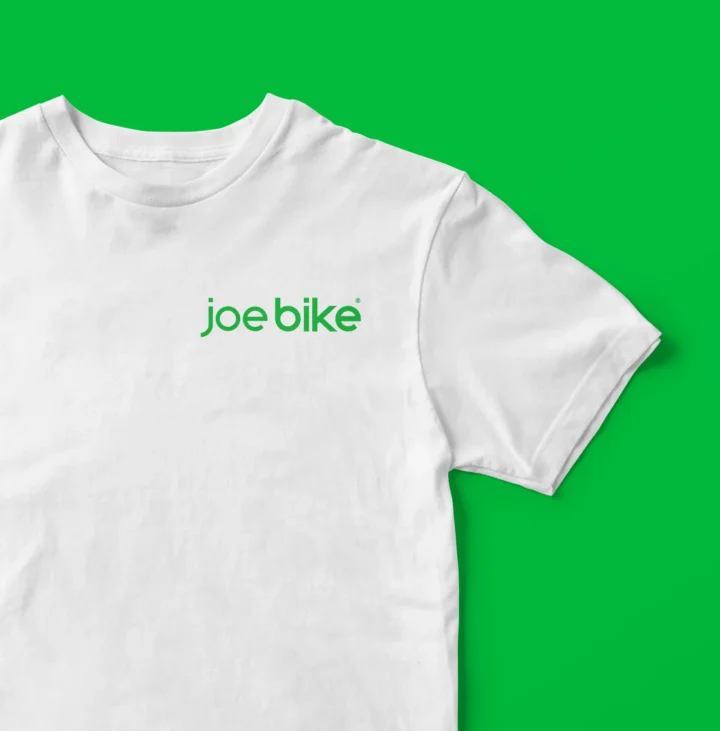 White Joe Bike T-shirt on a green background.